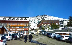 a group of cars parked in a parking lot with a snow covered mountain at Holiday House da Carlo in Catania