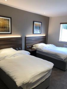a bedroom with two beds and two windows at Rivington Lodge in Bolton