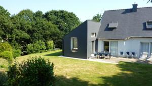 een huis met een zwart dak en een tuin met stoelen bij brest chambres d'hôtes in Brest