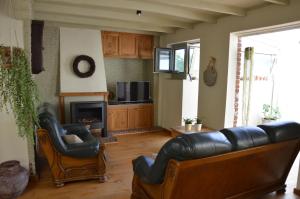uma sala de estar com um sofá de couro e duas cadeiras em 't bloemetje em Torhout