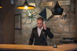 a man in a suit talking on a cell phone at Boutique Hotel Uniqato in Bansko