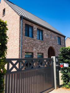 a house with a black fence and a brick building at De Karlapper in Lokeren