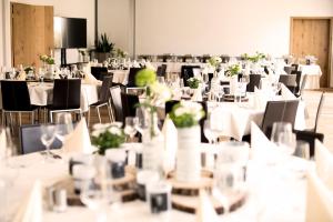 ein Raum voller Tische und Stühle mit weißen Tischdecken in der Unterkunft Hotel Linde in Günzburg