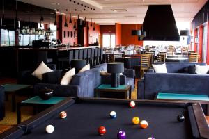 a pool table in a room with couches and a bar at Hotel Da Montanha in Pedrógão Pequeno