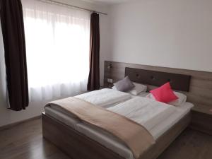 ヴィッラーニにあるRozé Vendégházのベッドルーム1室(大型ベッド1台、赤い枕2つ付)