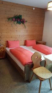 トゥクスにあるJunser Gasthauslのベッドルーム1室(赤いシーツと椅子付きのベッド1台付)