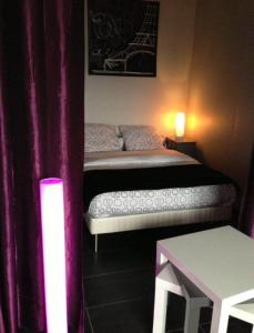 1 dormitorio con 1 cama con cortinas moradas y mesa en Appartement Les Confidences, en Le Touquet-Paris-Plage