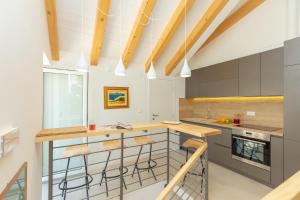 una cucina con armadi grigi e bancone con sgabelli di Apartment Hedera A56 a Dubrovnik