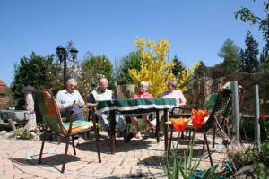 um grupo de pessoas sentadas em torno de uma mesa em um jardim em Ferienhaus Krug em Muhr amSee