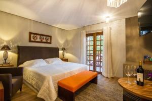 1 dormitorio con 1 cama y 1 mesa con copas de vino en Pousada Cantinho da Serra, en Campos do Jordão