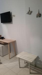 a wooden bench next to a table and a television at Casa Barbara in Marzamemi