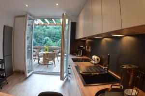 - une cuisine avec vue sur une terrasse dotée d'une table dans l'établissement 4 rue du Balloir, à La-Roche-en-Ardenne