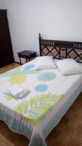 a bed with a colorful blanket on top of it at Hotel Tourist Araranguá in Araranguá