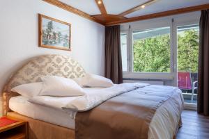 Bett in einem Zimmer mit einem großen Fenster in der Unterkunft Hotel Beau Rivage in Zermatt