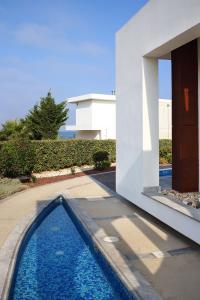 una casa con piscina al lado de un edificio en Paradise Cove Luxurious Beach Villas, en Pafos