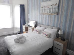 a bedroom with a white bed with towels on it at The Denewood in Sandown