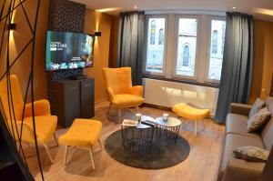 a living room with yellow chairs and a tv at 4 rue du Balloir in La Roche-en-Ardenne