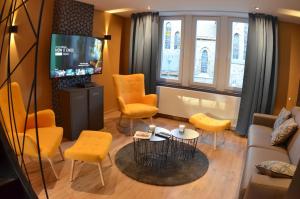 een woonkamer met gele stoelen en een tv bij 4 rue du Balloir in La-Roche-en-Ardenne