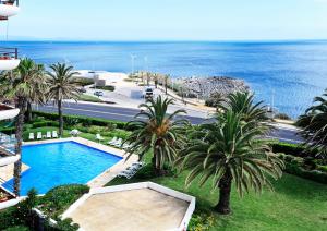 una vista aérea de una piscina con palmeras y el océano en Ocean View in Estoril - Checkinhome, en Estoril