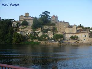 a castle on a hill next to a body of water at Hôtel Bellevue in Puy-lʼÉvêque