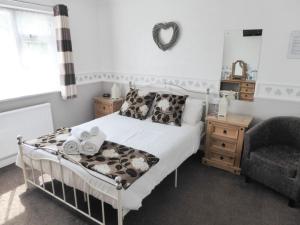 a small bedroom with a bed and a chair at The Denewood in Sandown