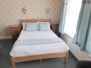 a bedroom with a large bed with blue pillows at The Denewood in Sandown