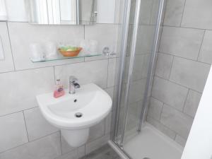 a white bathroom with a sink and a shower at The Denewood in Sandown