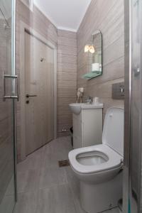 ein Badezimmer mit einem WC, einem Waschbecken und einem Spiegel in der Unterkunft Hotel H in Eforie Nord