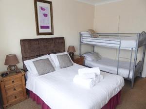 a bedroom with two beds and a bunk bed at The Denewood in Sandown