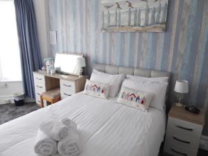 a bedroom with a white bed with towels on it at The Denewood in Sandown