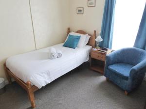 a bedroom with a bed and a blue chair at The Denewood in Sandown