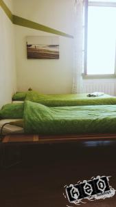 two beds in a room with green sheets and a window at h2oholidays for you in Capbreton