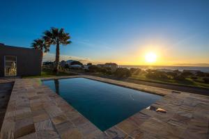 a swimming pool with the sunset in the background at Benguela in Gansbaai