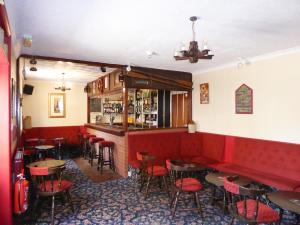 a bar with red seats and tables in a restaurant at The Denewood in Sandown