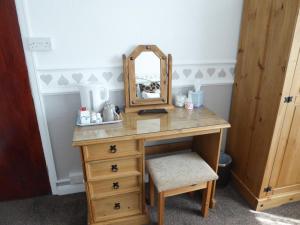a dressing table with a mirror and a stool at The Denewood in Sandown