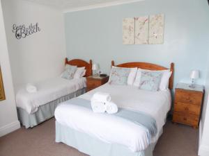 a bedroom with two beds with towels on them at The Denewood in Sandown