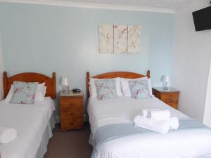 a bedroom with two beds with towels on them at The Denewood in Sandown