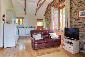 a living room with a leather couch and a tv at Tregolls Farm Cottages in Wadebridge