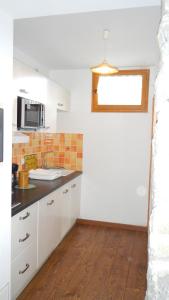 a kitchen with white cabinets and a sink and a window at Station de montclar in Saint-Jean