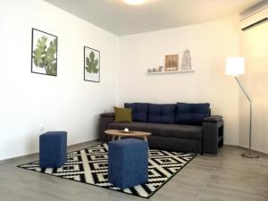 a living room with a couch and two blue stools at Maiv Apartments in Rogoznica