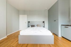 - un lit blanc dans une chambre blanche dotée de parquet dans l'établissement Sunny Riverside Apartments, à Prague