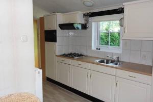 een keuken met witte kasten, een wastafel en een raam bij Vakantie veluwe in Wageningen