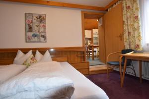 um quarto com uma cama, uma secretária e uma mesa em Pension Lenz em Ischgl