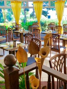 a restaurant with tables and chairs with yellow curtains at Hotel-Marks-Garni in Zingst