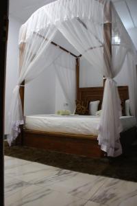 a bedroom with a canopy bed with white curtains at Sigiriya Lahiru Homestay in Sigiriya