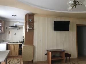 een keuken met een televisie aan een muur met een tafel bij Apartments Private in Truskavets
