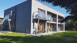 a white building with a balcony and stairs on it at WODNIK usługi hotelarskie, apartamenty in Rowy