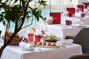 a table with glasses of wine and a plate of food at Hôtel Barrière Le Majestic Cannes in Cannes