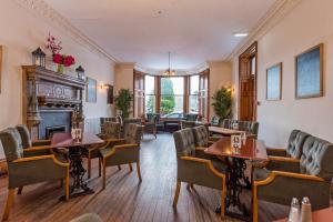 a waiting room with tables and chairs and a fireplace at Nethybridge Hotel in Nethy Bridge