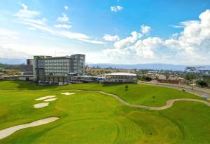un campo de golf verde con un edificio en el fondo en Punta Diamante Premium Hotel, en Bucaramanga